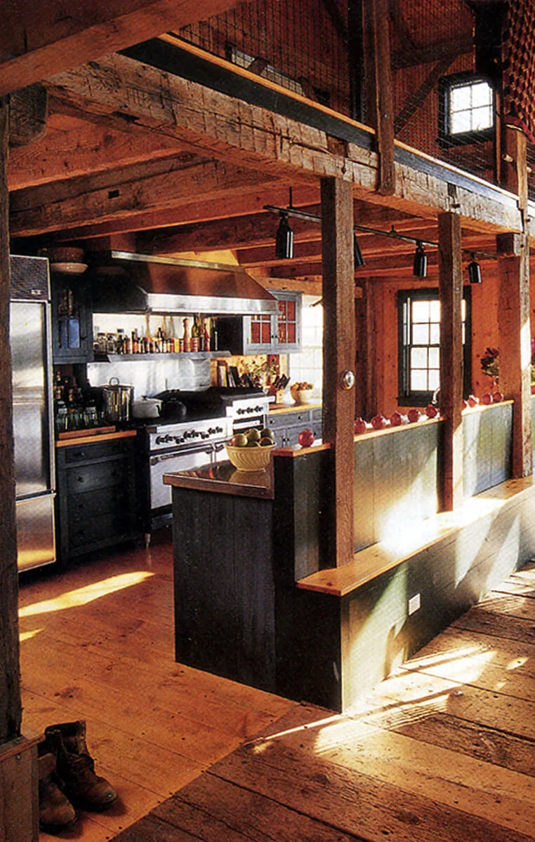 The kitchen in the Middleton-Waln Barn Home features exposed wood beams and a stainless steel range in a rustic barn-style setting.