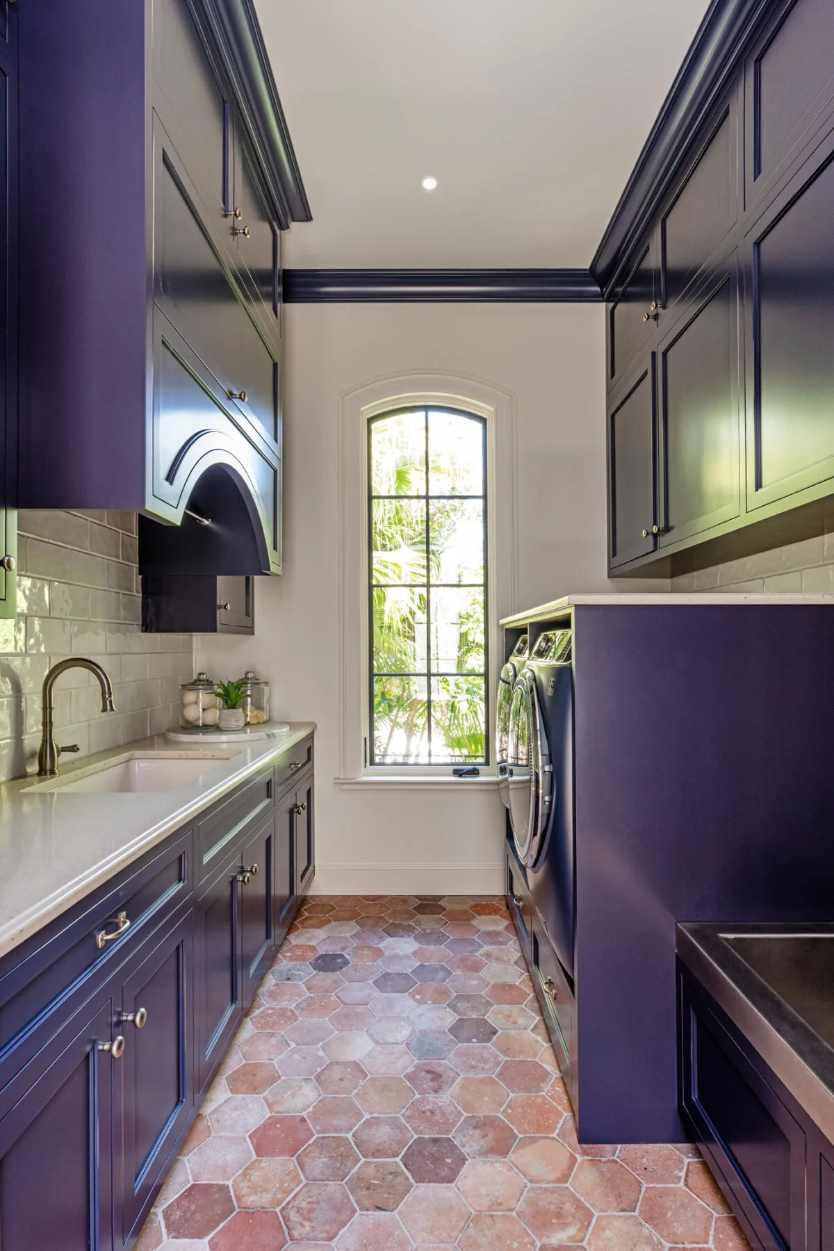 Laundry room with navy blue cabinetry, white countertop, and front-loading washer and dryer under counter.