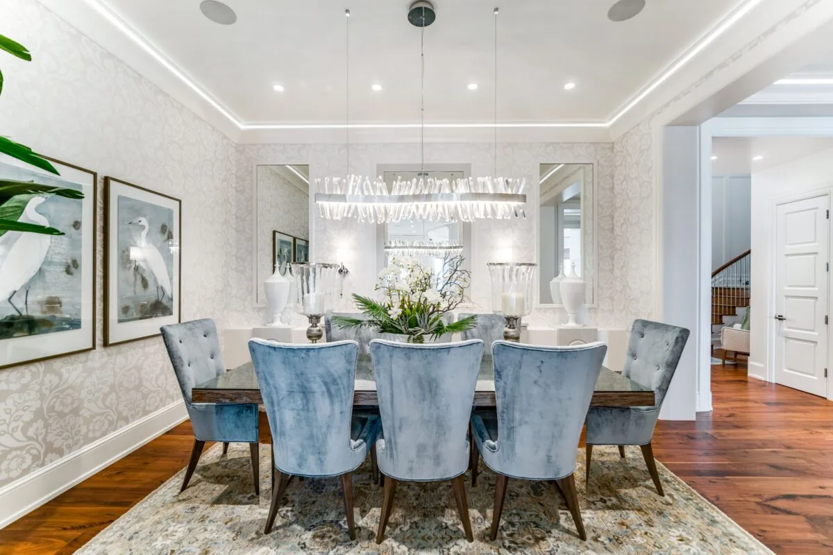 Dining room featuring velvet chairs, patterned wallpaper, and a modern linear pendant light.