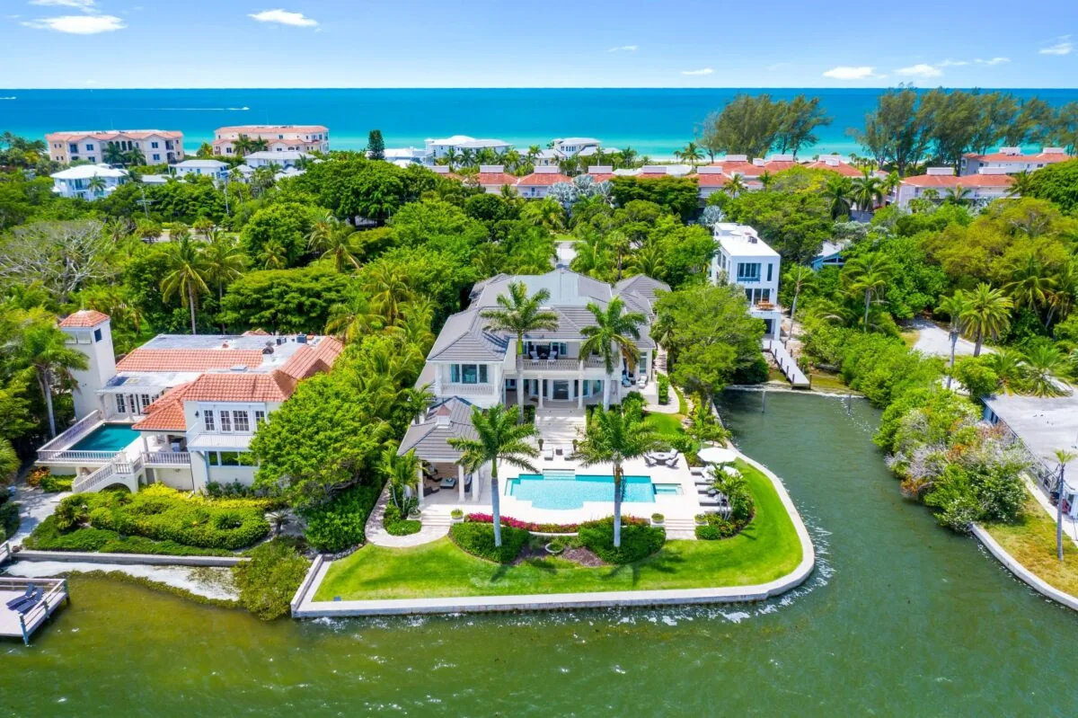 The Acqua Vita Bayfront Residence features waterfront views, a pool, and lush palm tree landscaping.