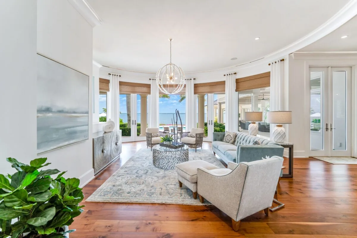 Acqua Vita living room with curved windows, velvet sofa, wooden blinds, and hardwood floor.
