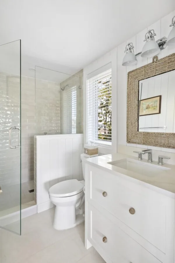 Bathroom features a walk-in shower with glass door and white cabinetry vanity with quartz countertop.