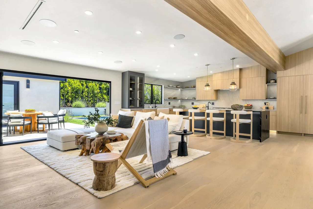 Open-concept living and kitchen area with black-framed bi-fold doors leading to a patio and garden at White Sails Residence.