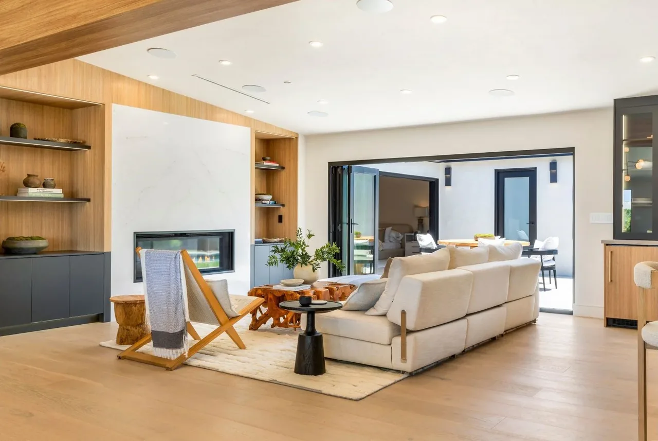 Living space featuring a built-in fireplace and bi-fold doors opening to a patio at the White Sails Residence by ALIS Architecture.
