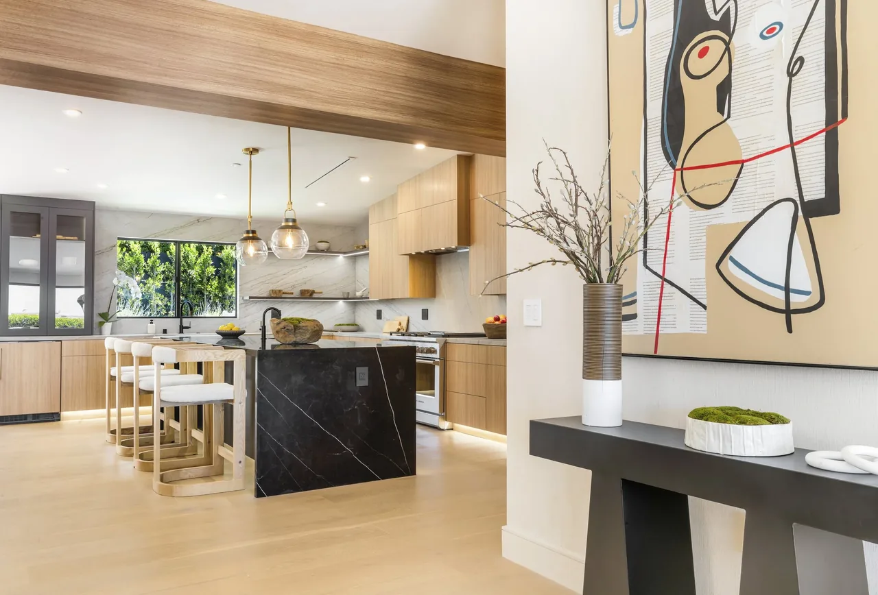 The White Sails Residence kitchen features a black marble island, light wood cabinetry, and pendant lighting above the island.