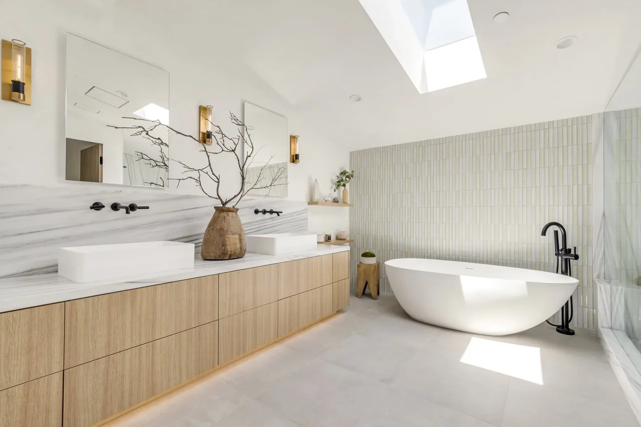 Bathroom featuring a freestanding tub, double vanity, and a skylight illuminating the space.