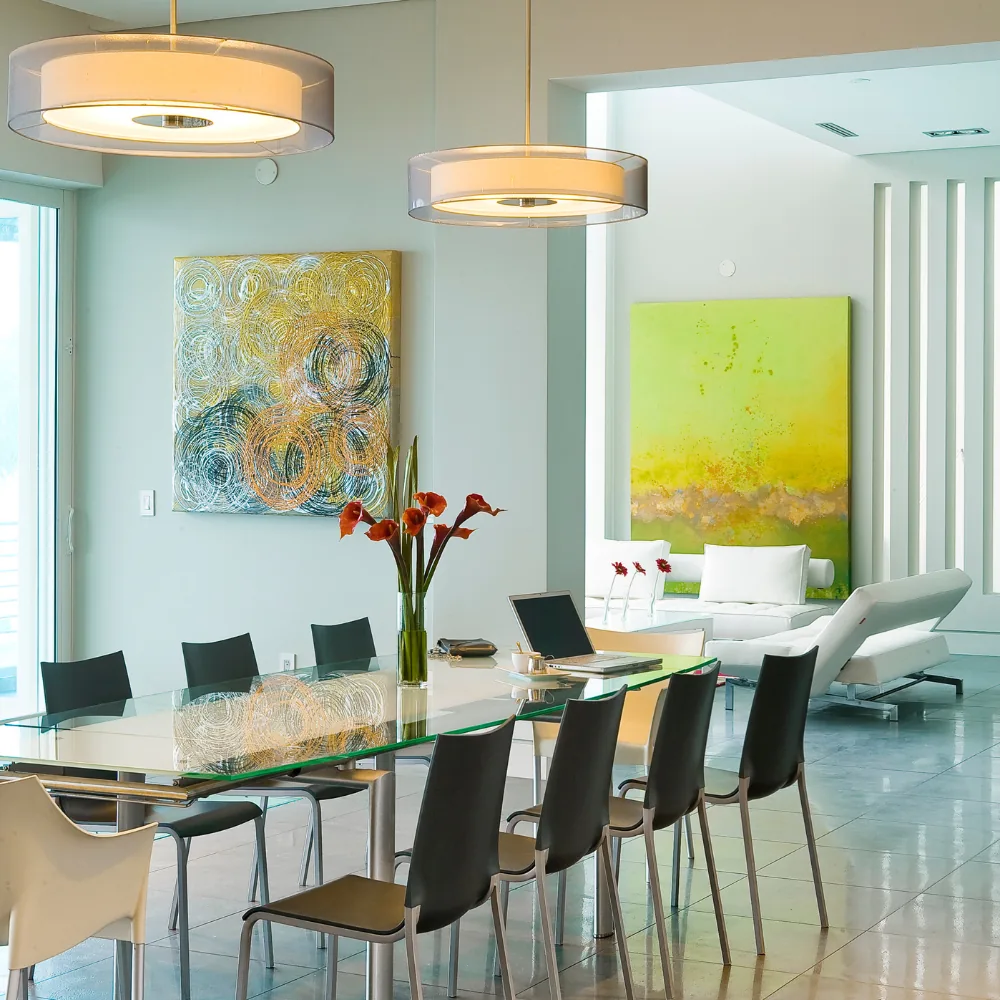 Contemporary dining room features a glass table with black chairs and modern pendant lighting.