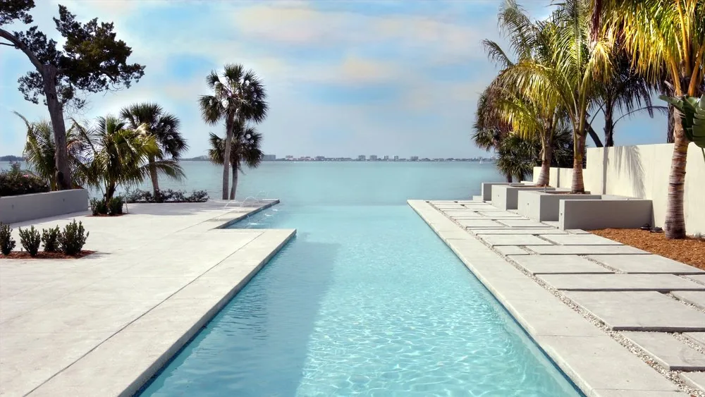 Infinity edge pool at Indian Beach Residence with surrounding palm trees and concrete decking.