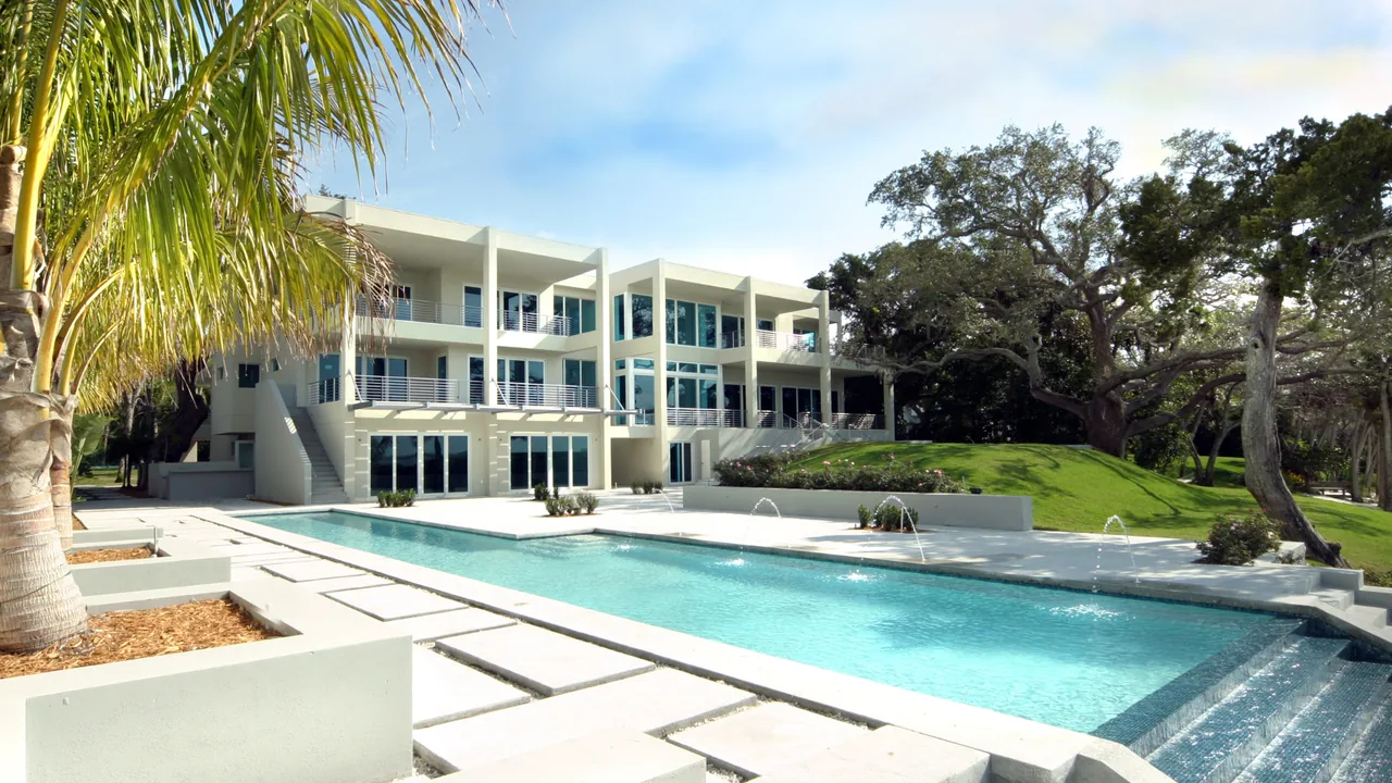 The Indian Beach Residence features a modern three-story design with horizontal metal railings and an outdoor pool with water jets.