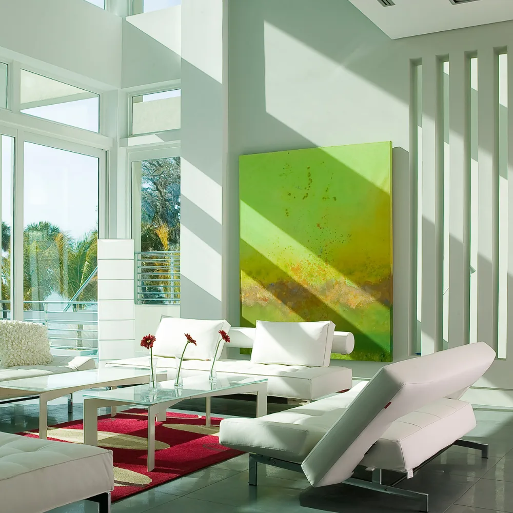 Living room with white leather seating, glass coffee table, and large green abstract art over a bright red rug.