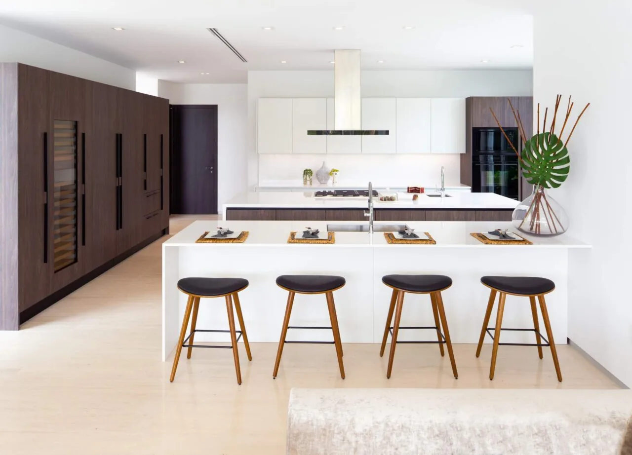 Contemporary kitchen with a white island bar, dark wood cabinetry, and integrated appliances at 301 Residence by SDH Studio Architecture + Design.