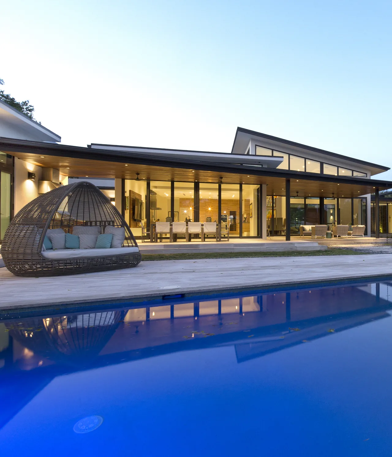 The ALF Residence features a cantilevered roof covering a spacious outdoor seating and dining area adjacent to a pool.