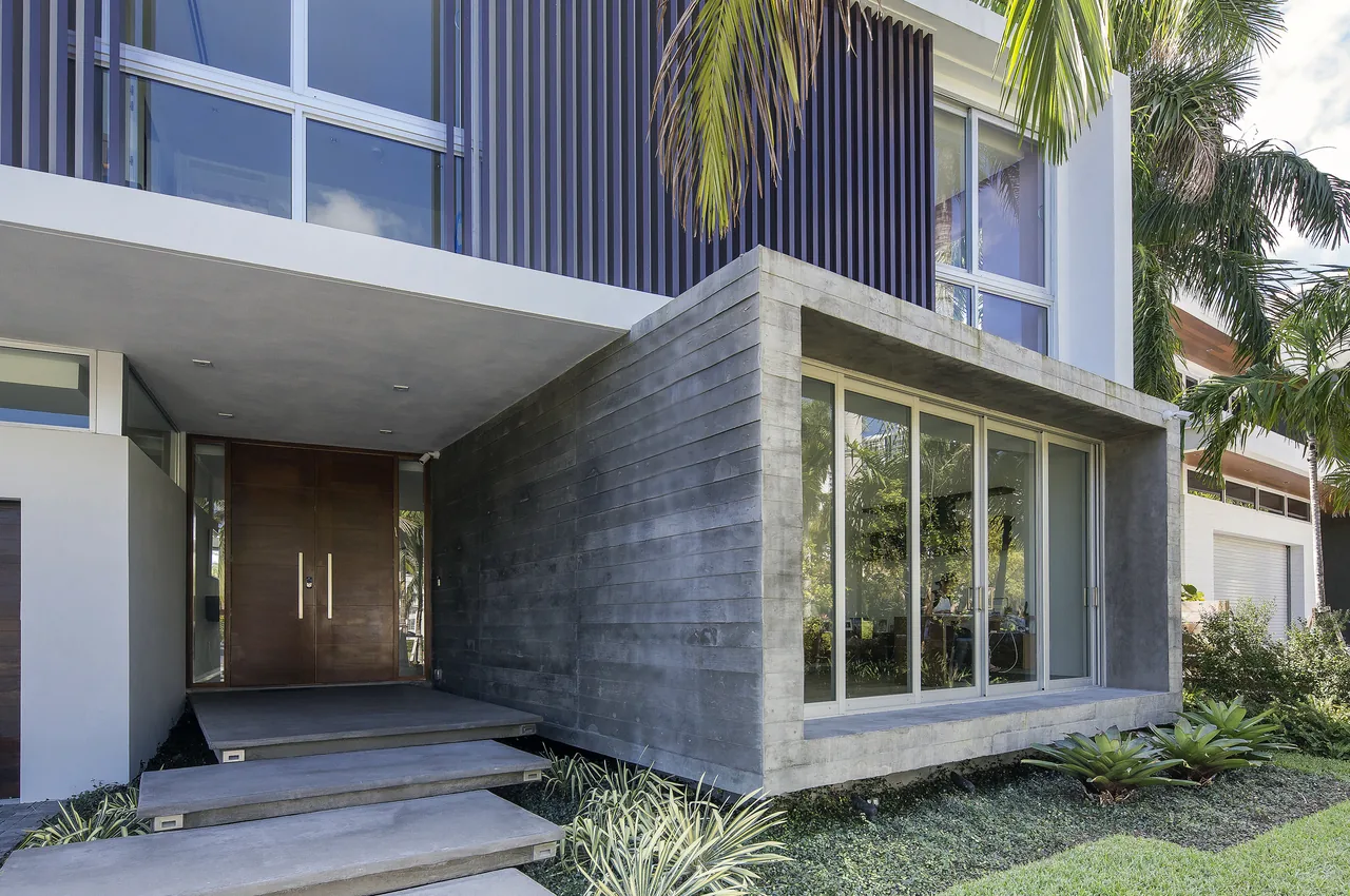 Wex Residence entrance featuring floating concrete steps and a cantilevered concrete window frame shows a modern architectural style.