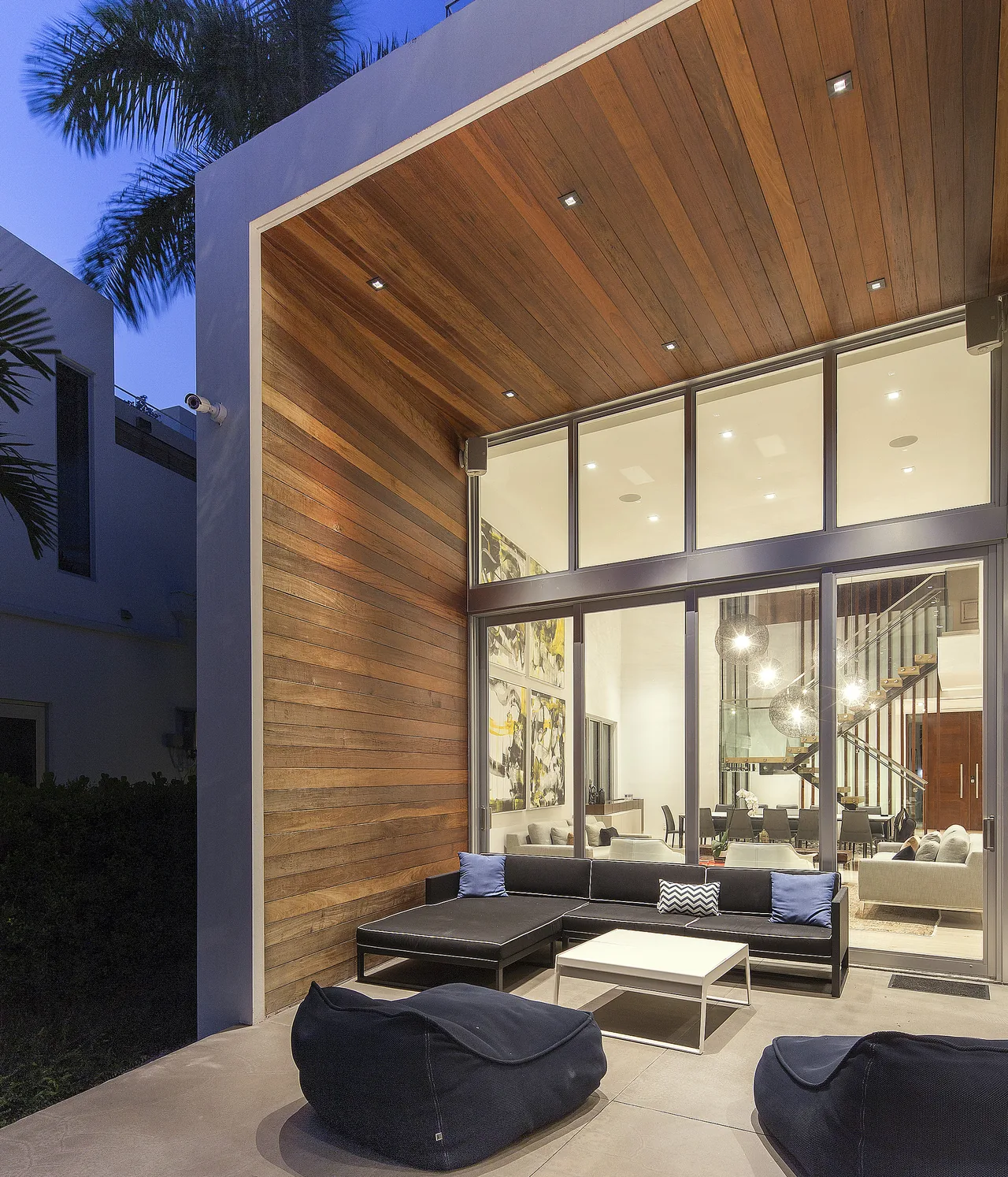 The Wex Residence features an outdoor seating area with wood-paneled ceiling and large sliding glass door opening to an interior living space.