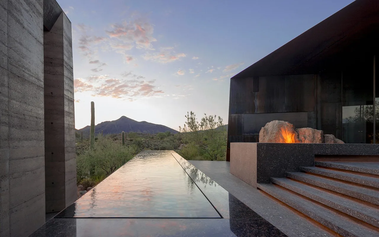 Water pool with fire feature and concrete steps in a desert setting at sunset at Desert Courtyard House.