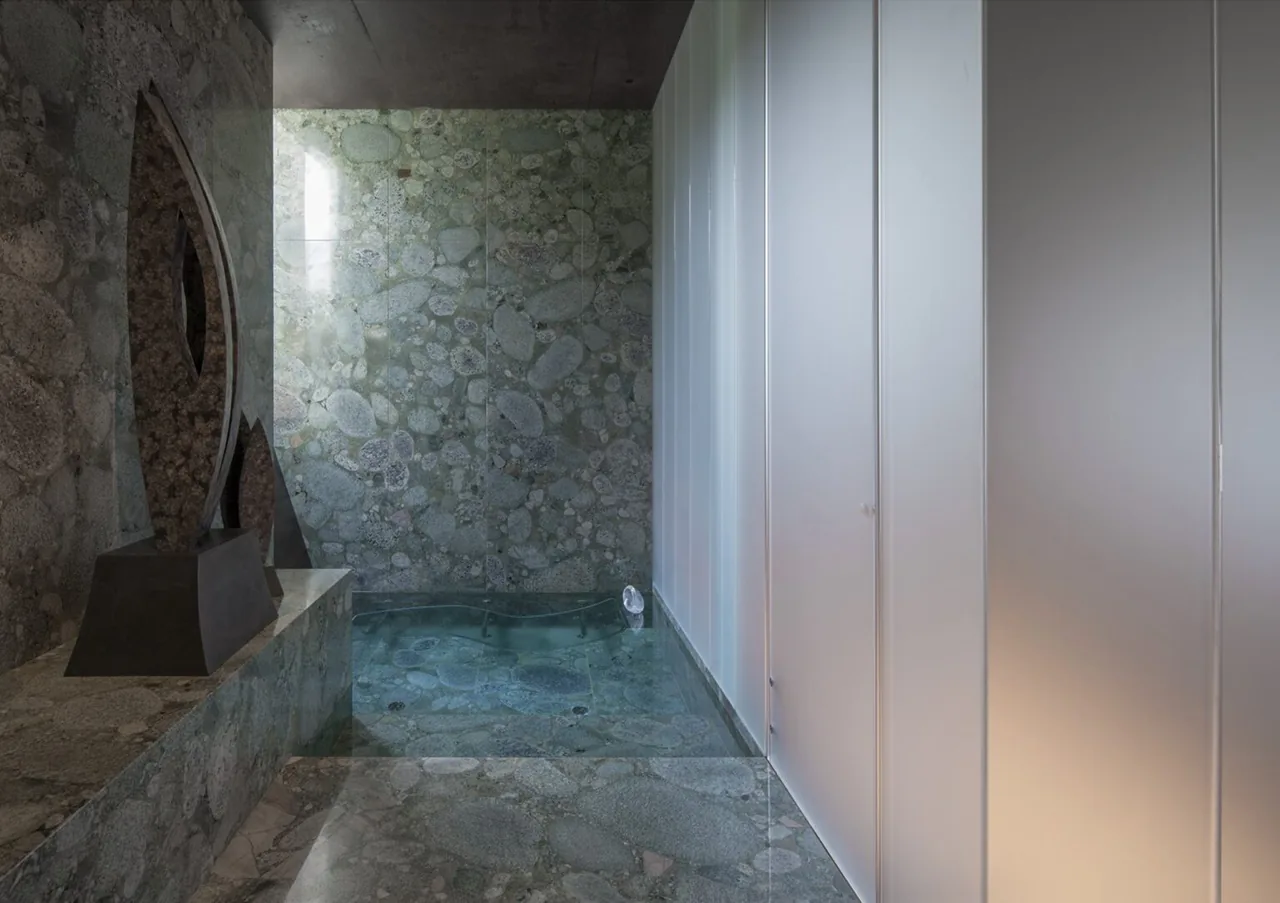 Reflective stone surfaces and a small water feature create a contemplative interior space in the Desert Courtyard House.