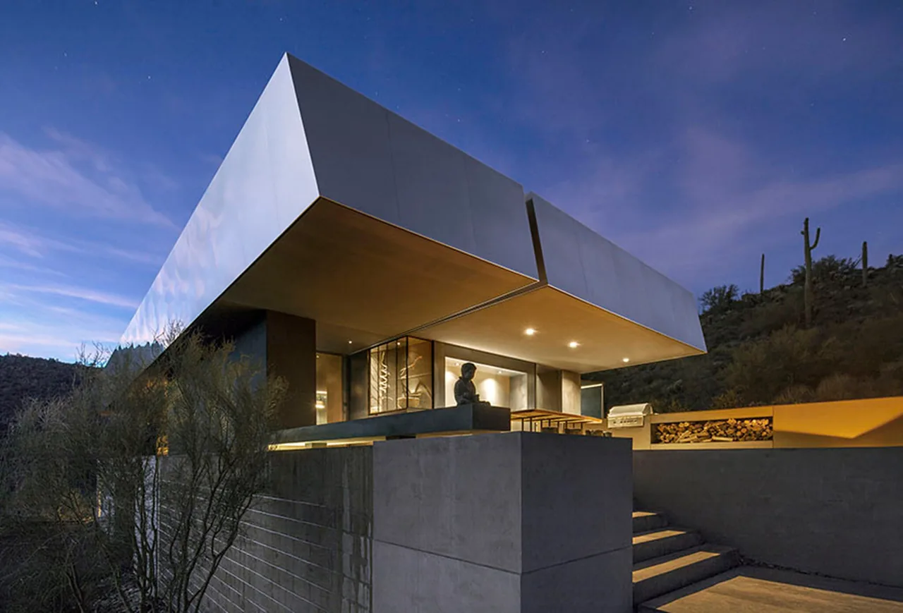 Hidden Valley Desert House features a striking cantilevered roof and stacked concrete walls overlooking a desert hillside.