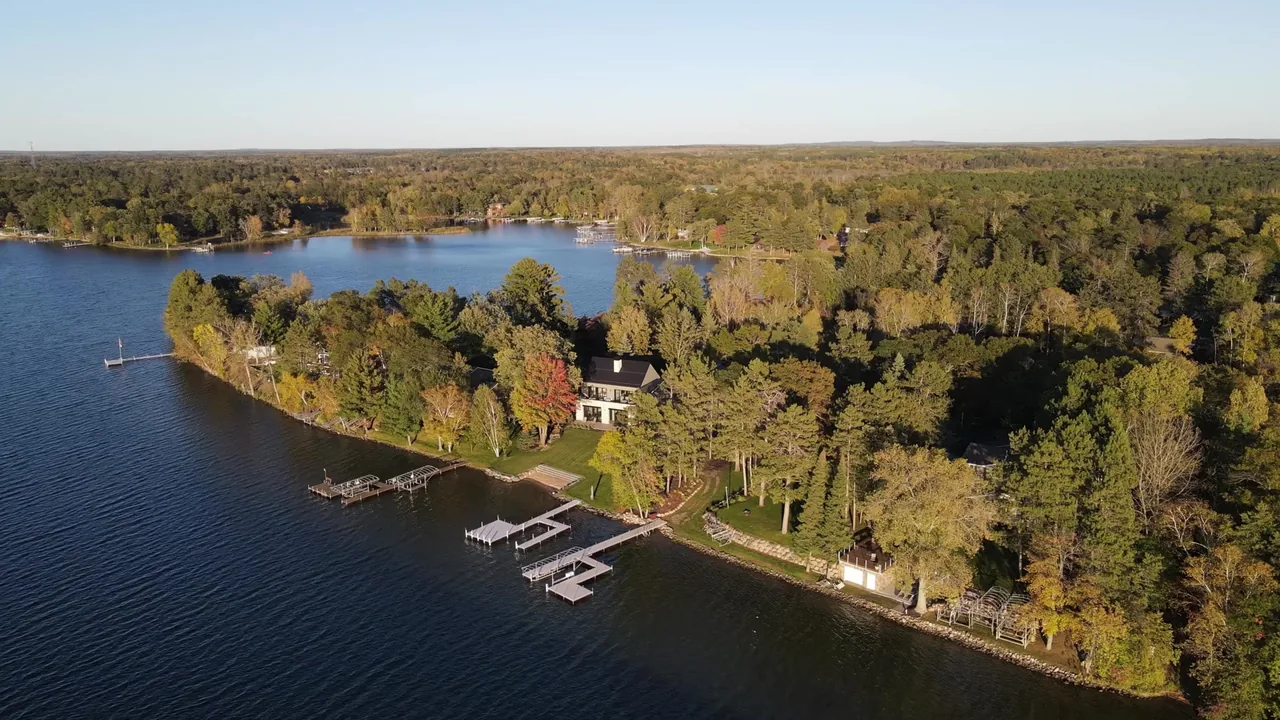 Whitefish Lakehouse sits on a wooded peninsula with multiple docks extending into the lake.