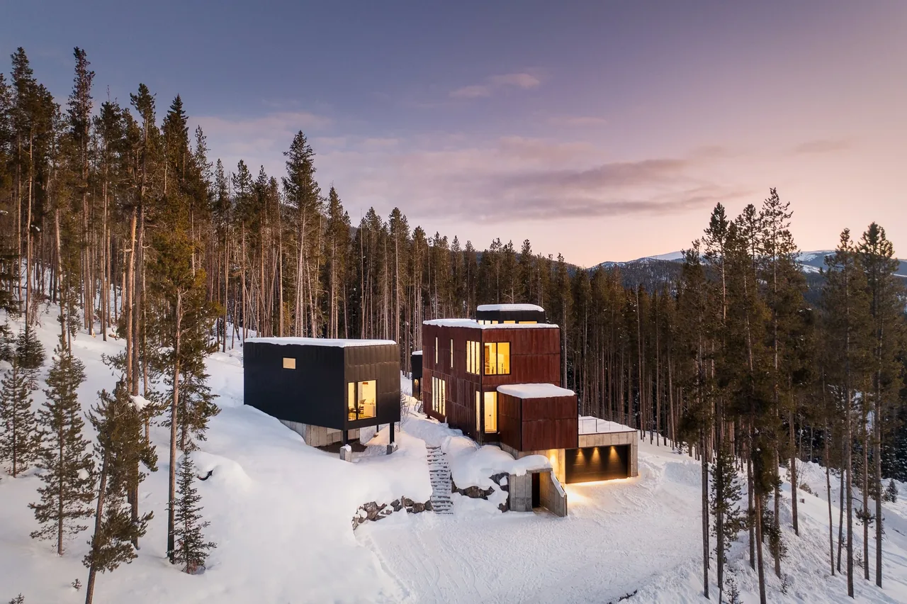 The GCR-8 project features a two-part modern house nestled in a snowy forested mountain area with expansive windows and a garage.