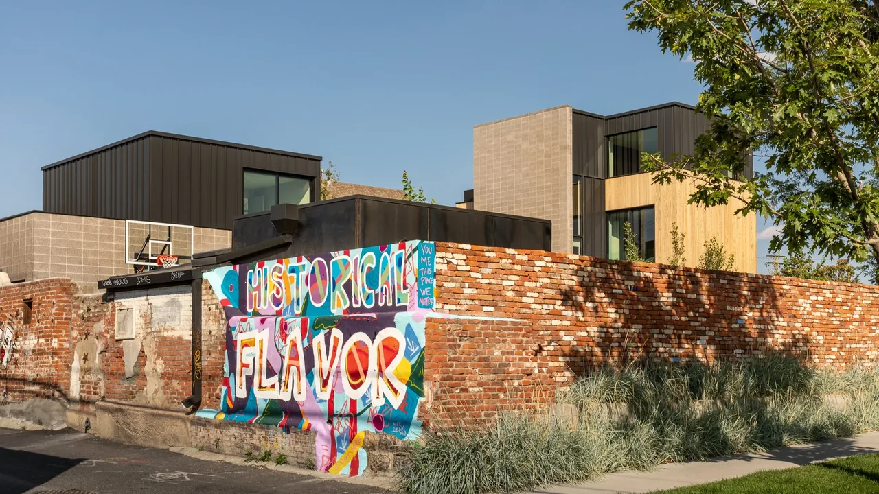 RiNo residence features a modern design with wood, concrete, and black metal behind a brick wall with graffiti.