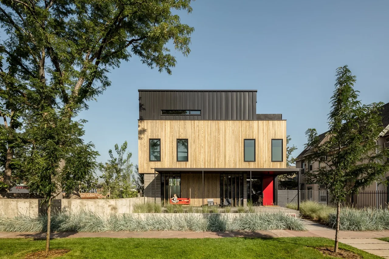 The RiNo residence features vertical wood siding with a black metal roof and a covered front patio.