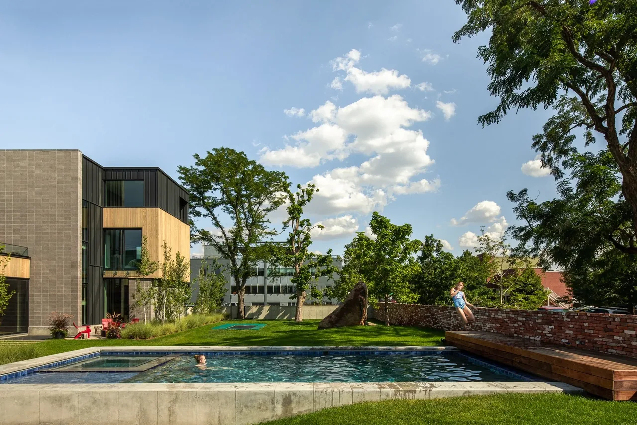 RiNo residence features a modern backyard with a swimming pool, integrated wooden bench, and landscaped grassy yard.