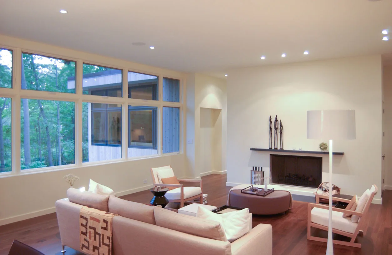 Living room of McAllister Road House features large white-framed windows and a minimalist fireplace.