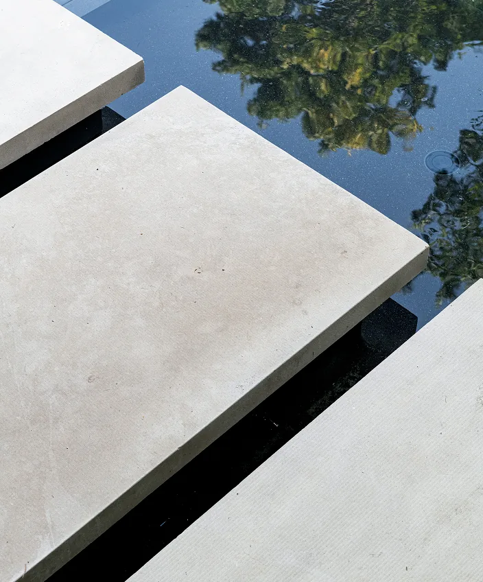 Floating concrete slabs form a walkway over a reflecting pool creating a modern water feature.