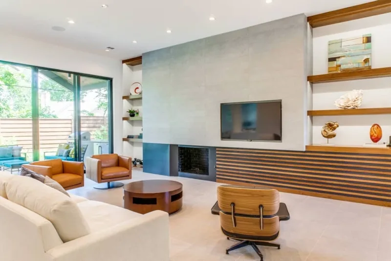 Living room features a concrete fireplace wall with wood slat paneling, built-in shelves, and sliding glass doors to an outdoor patio.