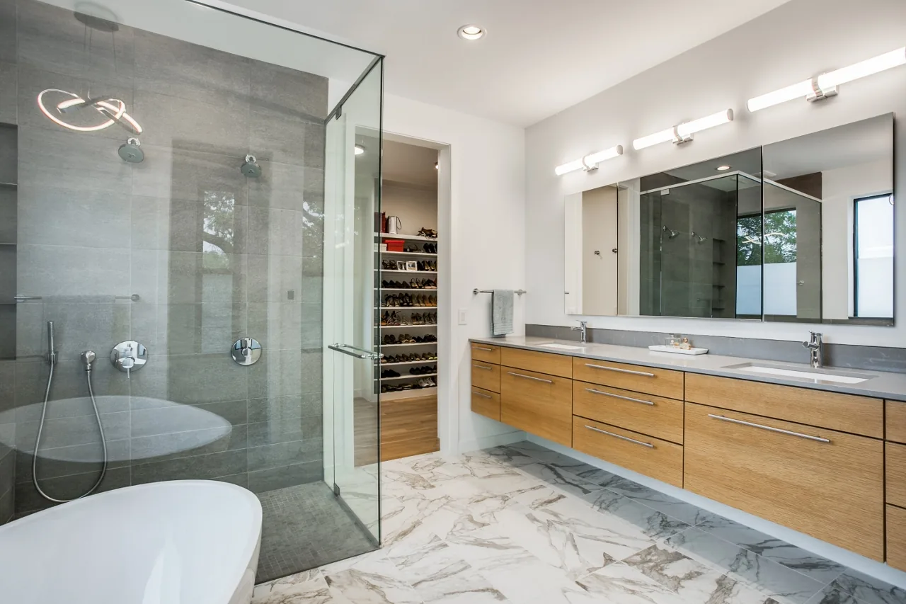 The bathroom features a floating wooden vanity with double sinks and a glass-enclosed shower with gray tile walls.