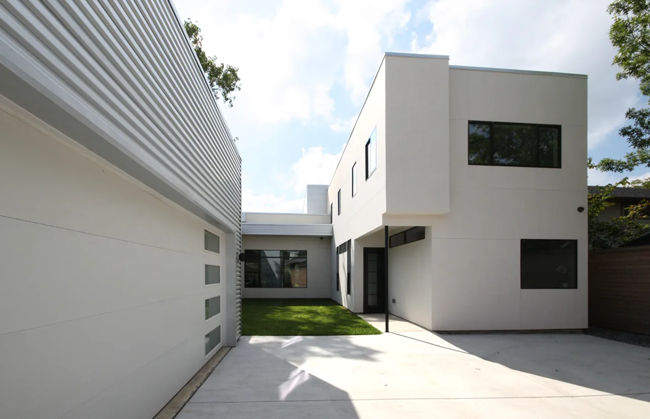 Exterior of Ribbon House in Dallas showing modern white facade with black windows and concrete driveway.