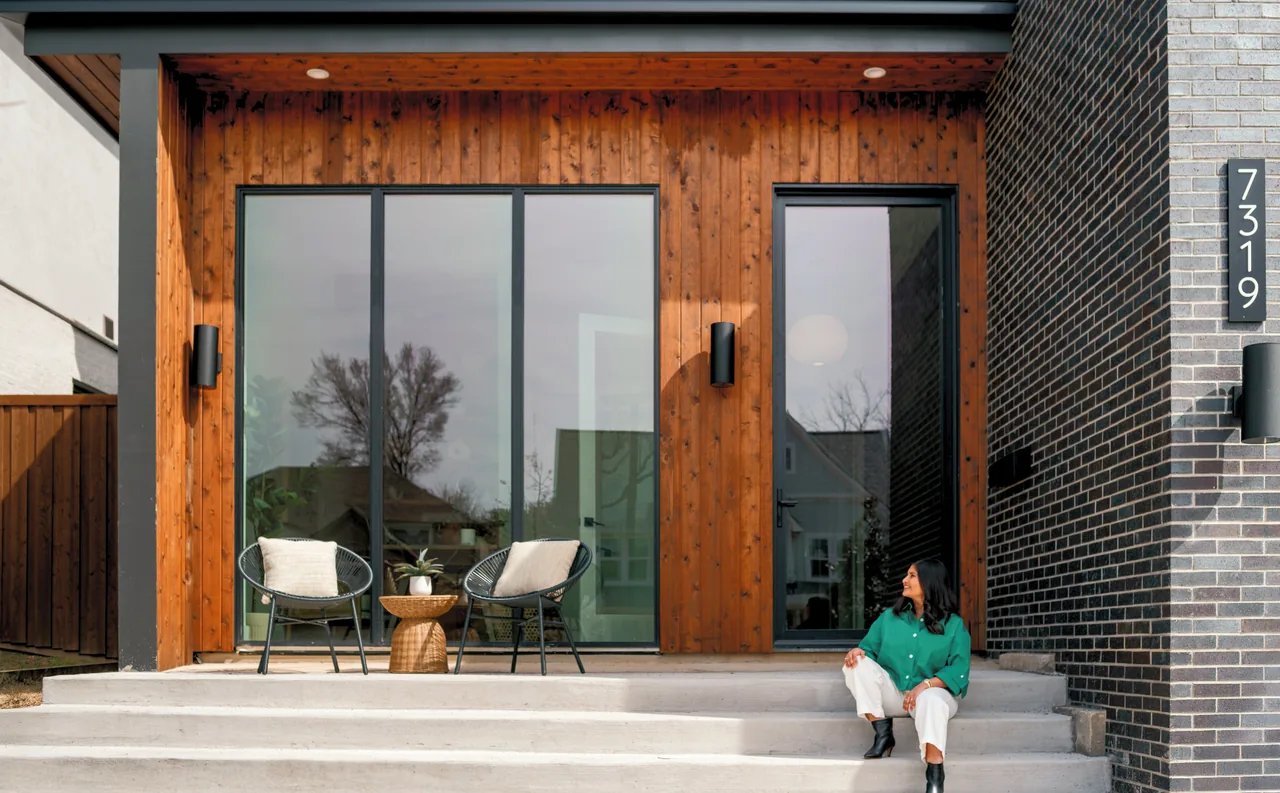 Casa Loma features a front porch with wood siding, floor-to-ceiling glass doors, and black window frames.