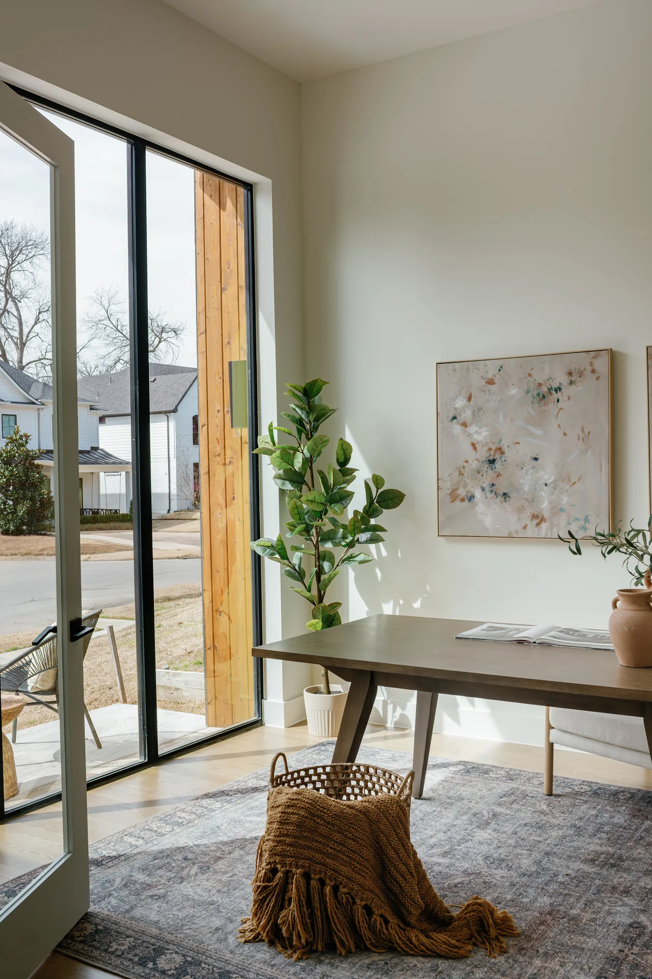 Office space with high ceilings and floor-to-ceiling windows opens to an outdoor seating area and garden.