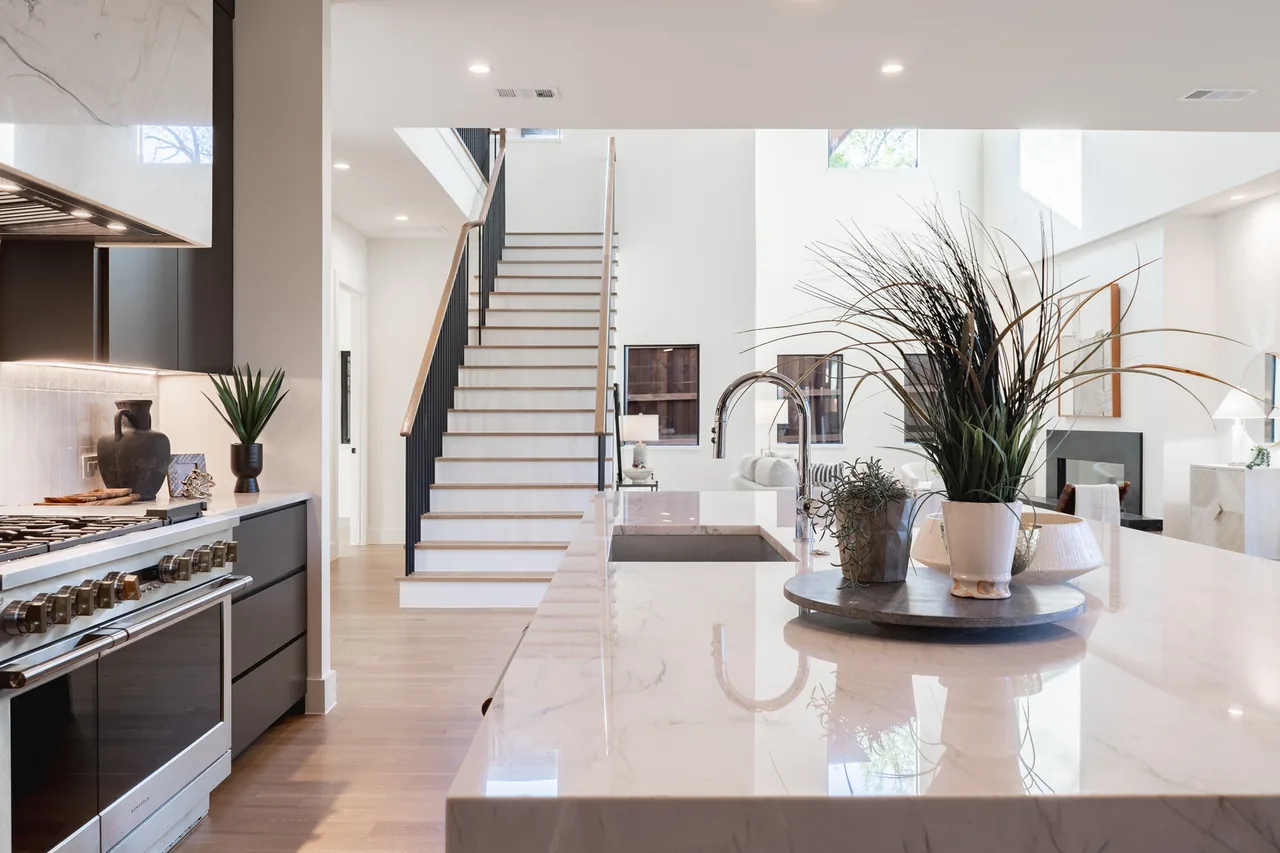 Modern open kitchen with marble island, wood flooring, and a staircase leading to the upper level in Casa Loma II.