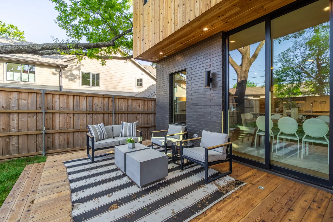 Patio deck with mixed seating furniture, concrete coffee tables, and a striped outdoor rug at Casa Loma II.
