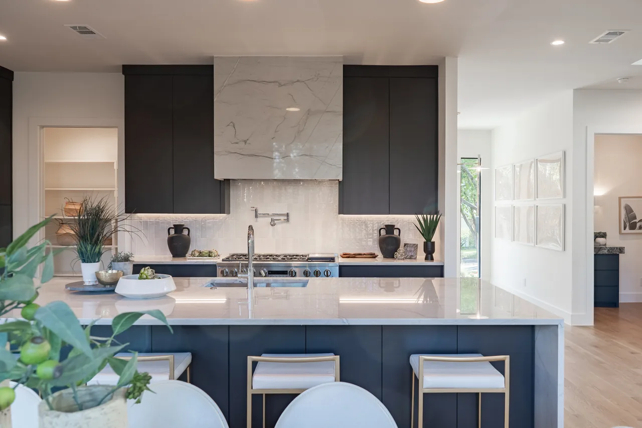 The kitchen features a large marble island with seating and black cabinets with a marble hood cover.