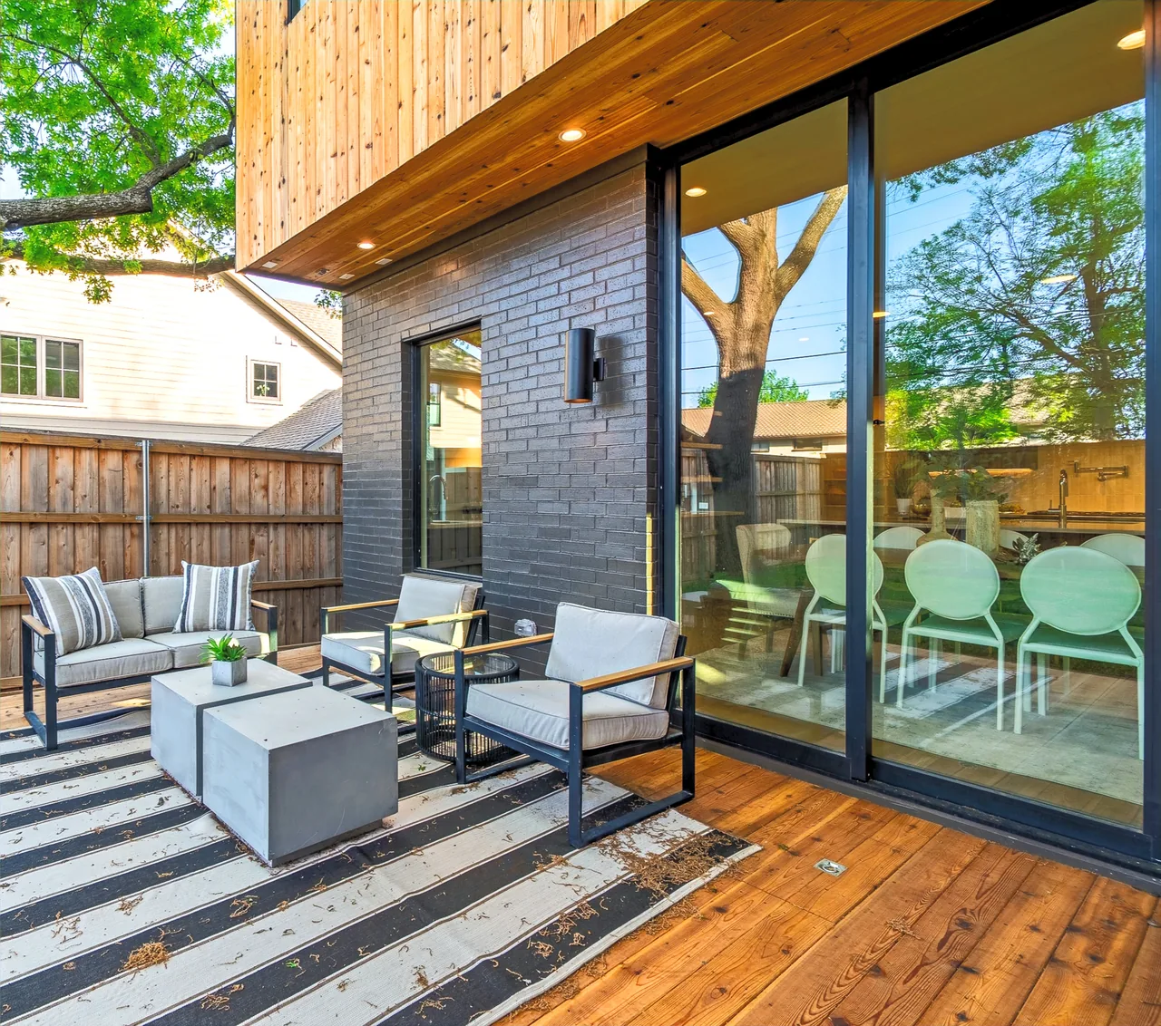 Modern outdoor living space with wooden deck and large sliding glass doors at Casa Loma II by F+E Architects.