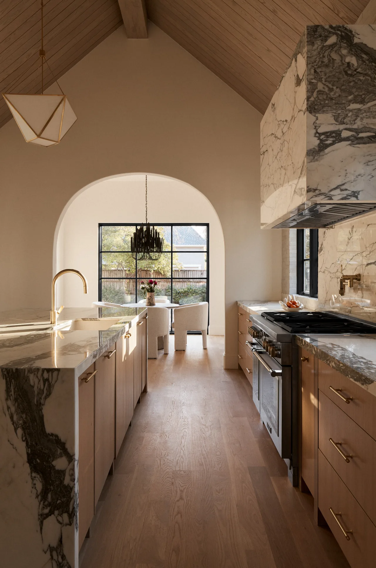Marble countertops and wood cabinetry fill this vaulted ceiling galley kitchen with an arched doorway leading to the dining space.