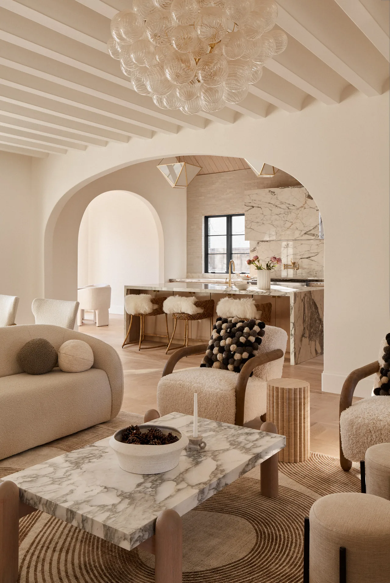 Living room features arched doorways, a marble coffee table, and a neutral palette highlighting texture and warmth.