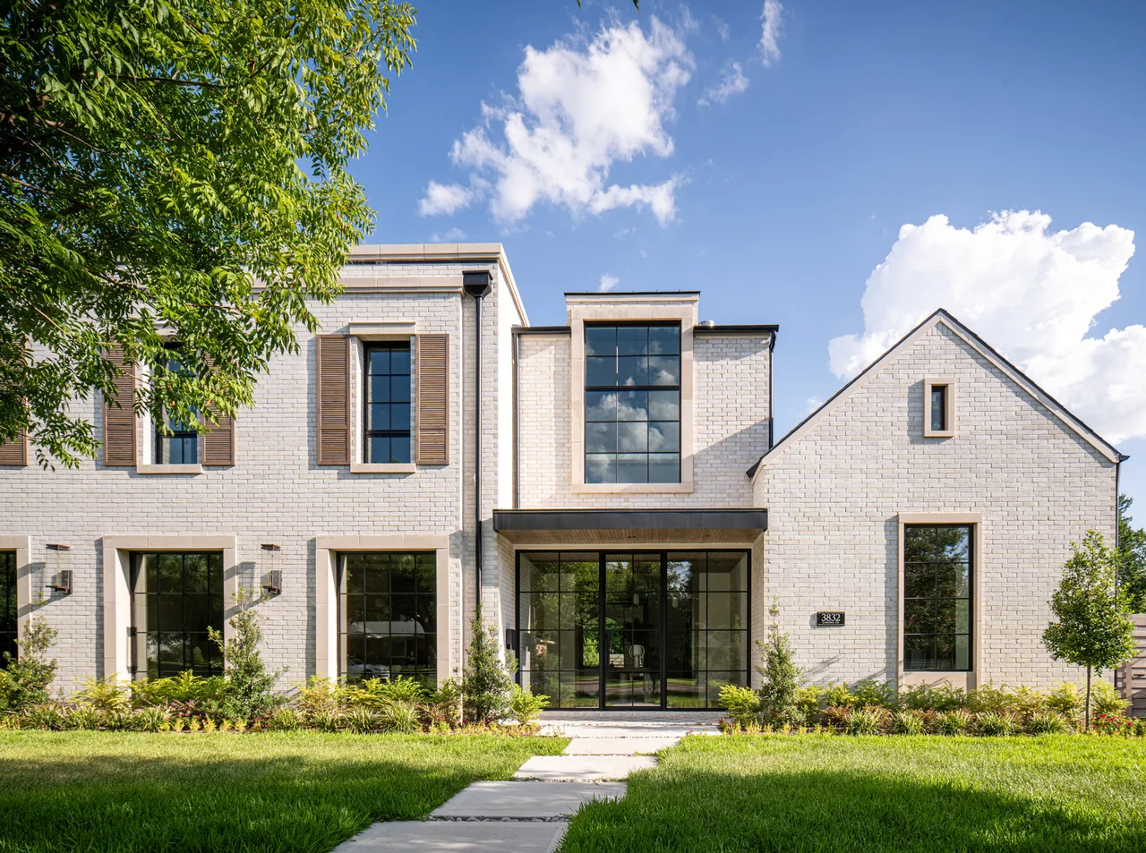 Modern white brick house with grid windows and wood shutters at the front exterior in Dallas.