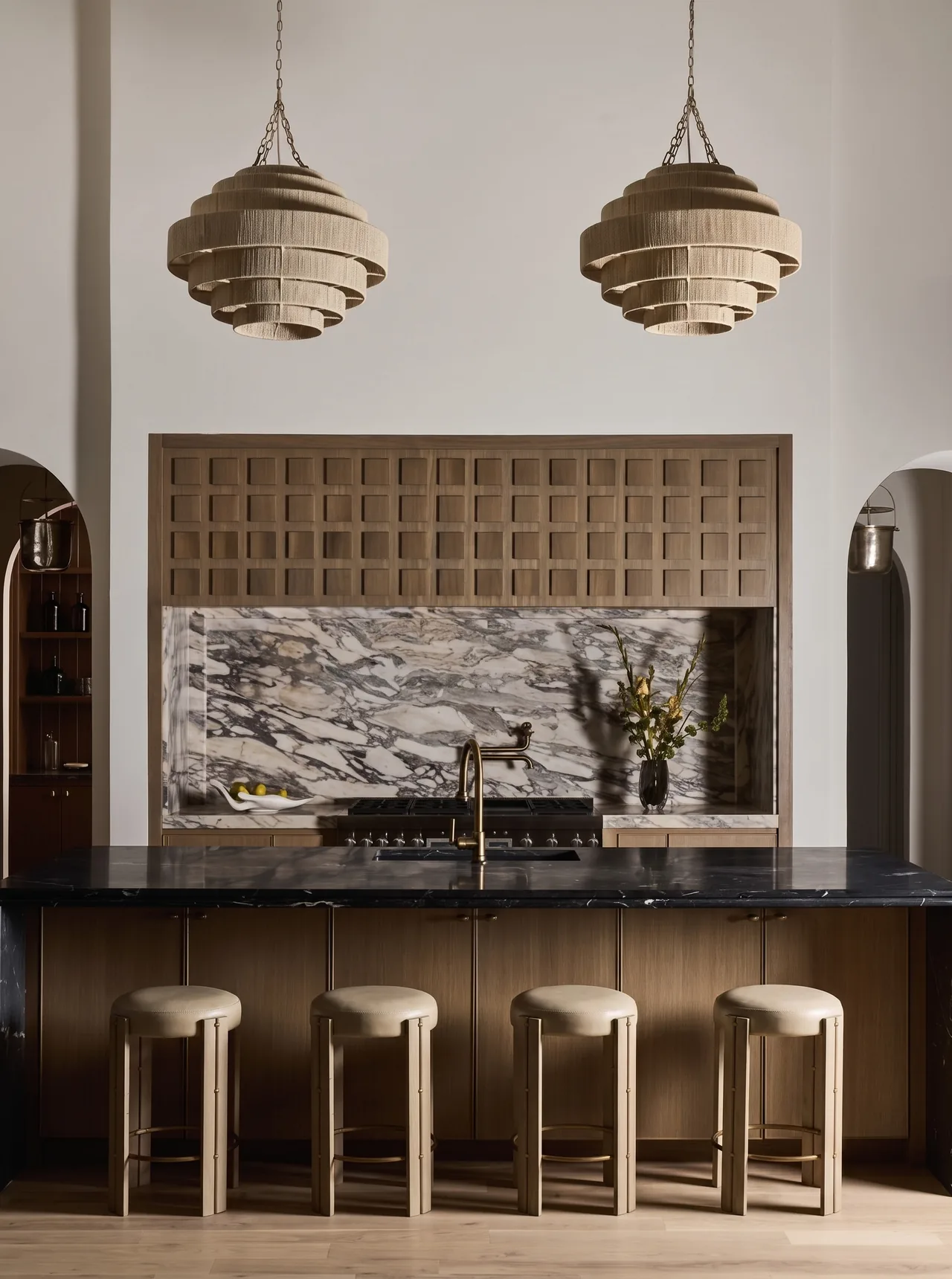 Kitchen featuring a black marble island, wood cabinetry, marble backsplash, and two pendant lights.