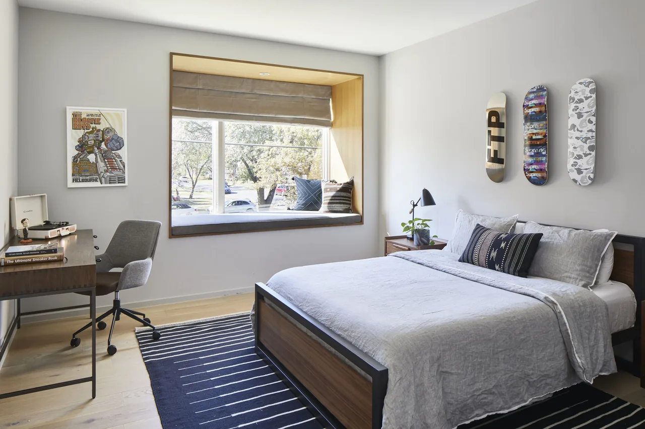 Bedroom with a wood-framed bed, window seat, and skateboard deck wall art at Vanderbilt Residence.