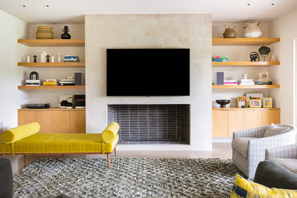 Living room of Vanderbilt Residence features a fireplace wall with TV and built-in shelving by Studio Park Architecture.