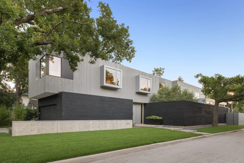 VANDERBILT RESIDENCE features vertical wood siding on the upper story and dark horizontal siding on the lower level, set among mature trees.
