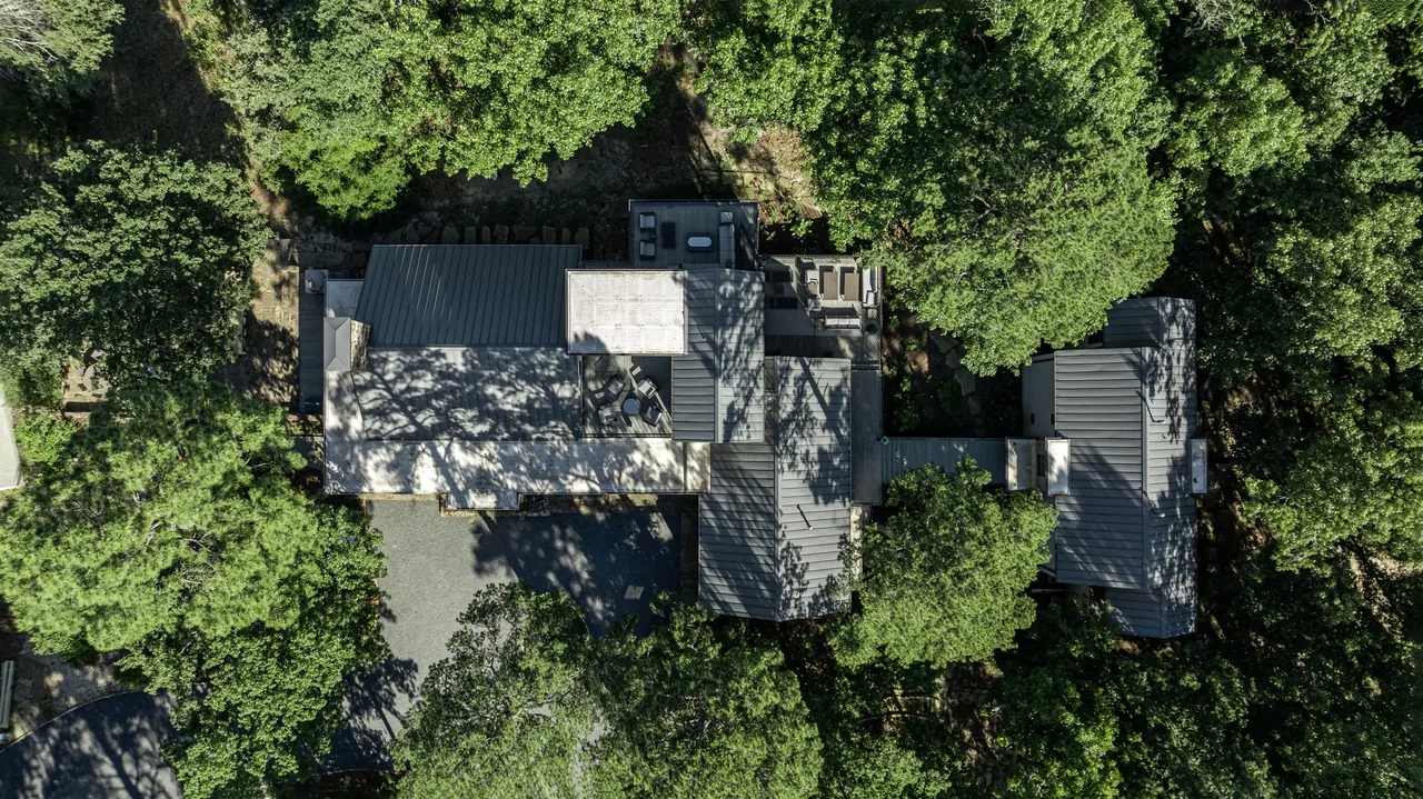 Pines Ranch features a modern design with metal roofing nestled in a wooded landscape.