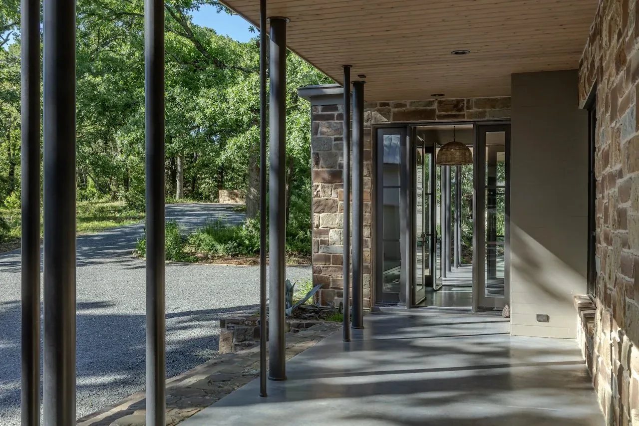 Shaded porch with stone wall and metal columns at Pines Ranch project.