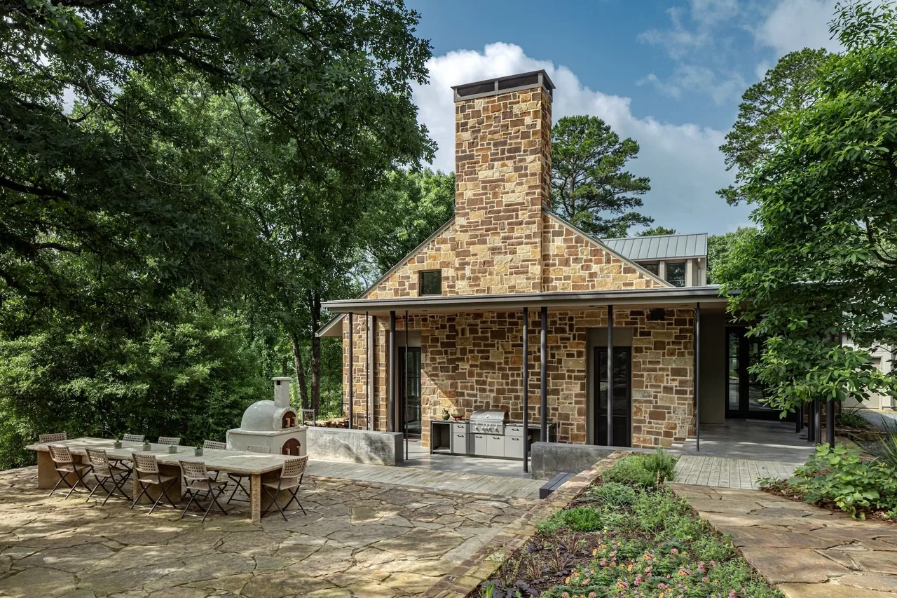 Pines Ranch features stone exterior with a metal roof, stone chimney, and outdoor kitchen on the patio.