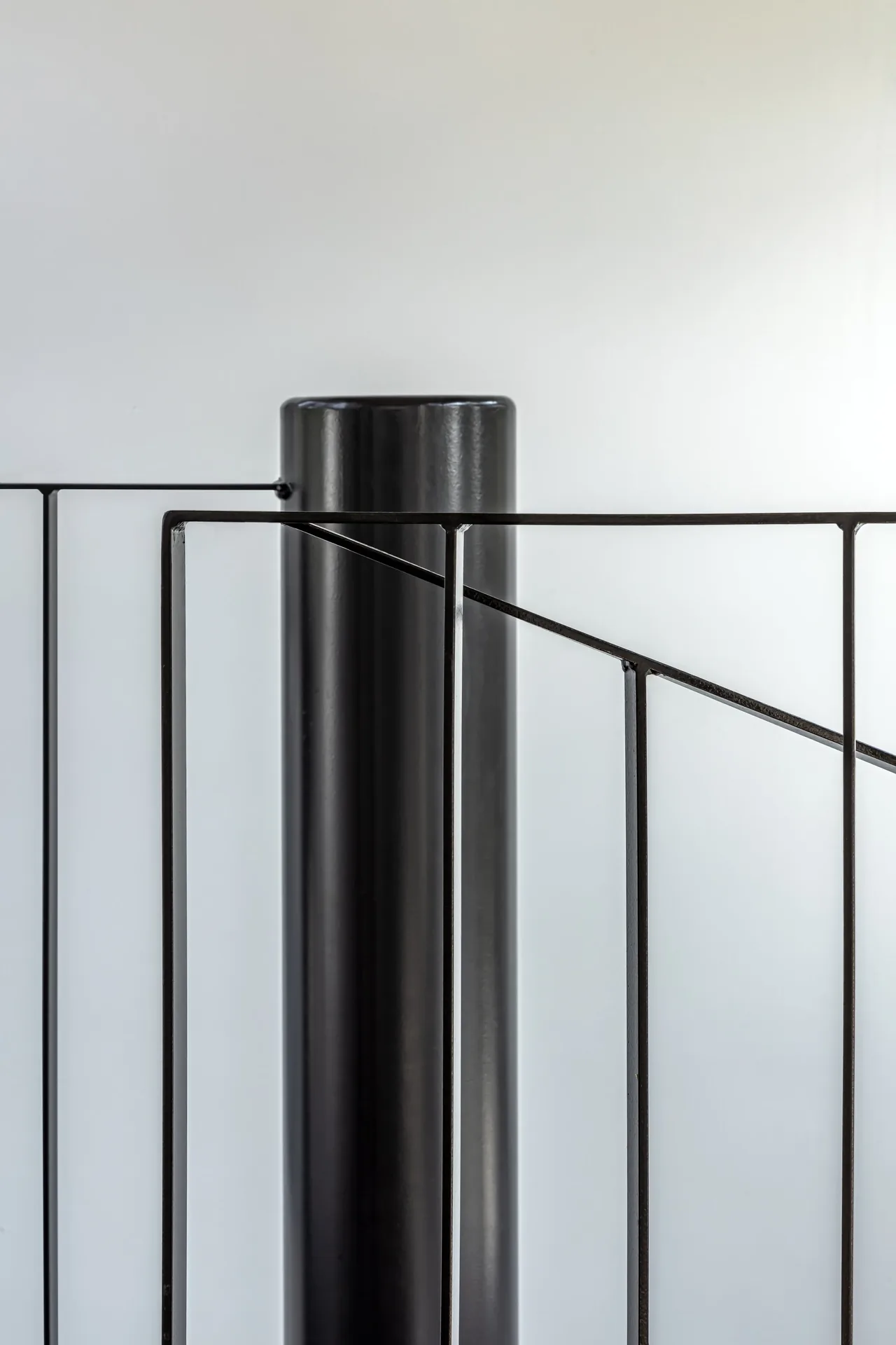 A black metal spiral stair railing with vertical and diagonal bars.