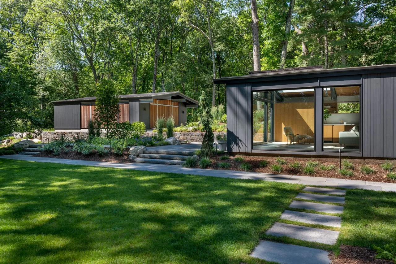 New Additions to Hoover + Hill feature modern buildings with vertical wood siding and large windows surrounded by a landscaped garden.