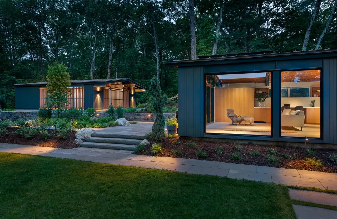 New additions to Hoover + Hill show modern buildings with horizontal windows and outdoor stone walkway, illuminated at dusk.